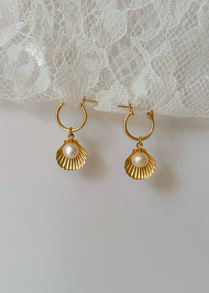 Gold hoop earrings with pearl drops on a lace background